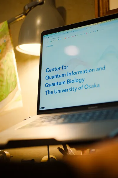Macbookの画面に、大阪大学 量子情報・量子生命研究センター(QIQB)サイトが表示されている