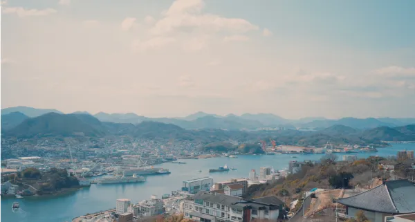 ALTはじまり：千光寺頂上展望台から見た、尾道の景色。手前に尾道市内、尾道水道を挟んだ対岸には、向島地区をはじめとする瀬戸内海の島々が一望できる。撮影日は心地よい風が吹くおだやかな海で、港には大きい船や工場が並んでいた。ALTおわり