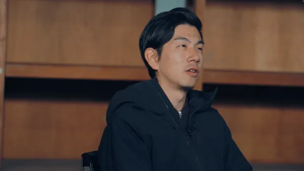 ALTはじまり：溝口さんが斜め上を向いて考えながら話している様子。黒いダウンジャケットを着用している。ALTおわり