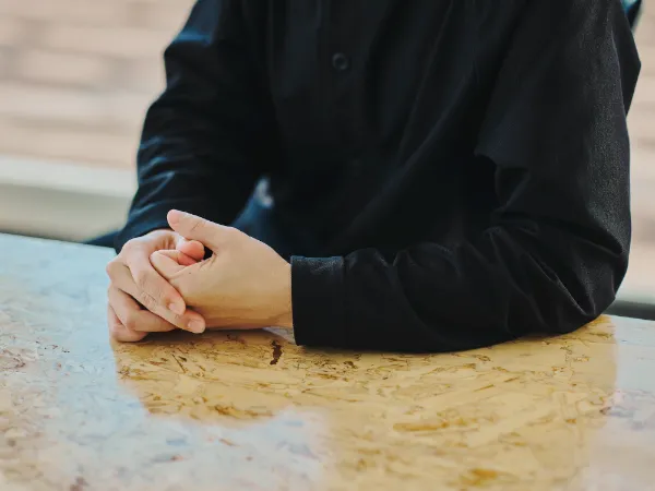 写真：テーブルの上で両手を組み、話を聞く櫻井さんの手元。