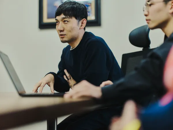 写真:藤原隆充さんが話している様子。手前には尾木さんの横顔とノートパソコンがある。