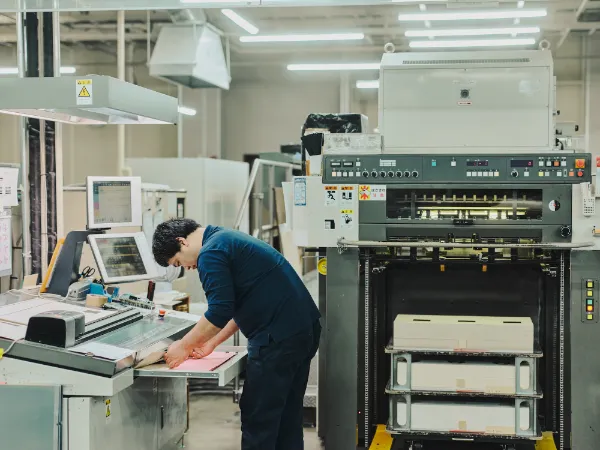 写真:藤原印刷の工場で、印刷機の前で作業を行うスタッフの姿。