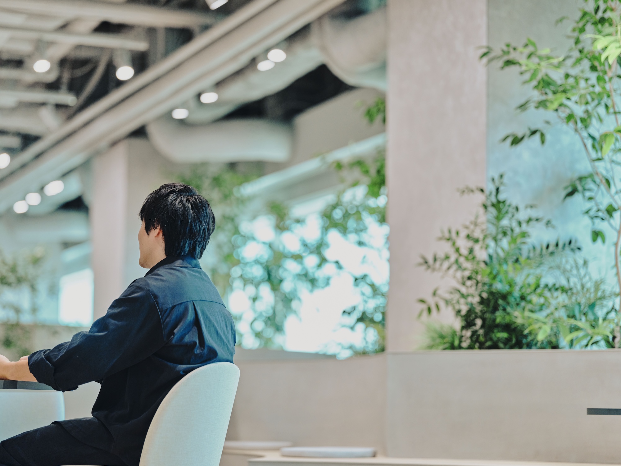 ALTはじまり:広々としたラウンジスペースと、兼原さんの後姿。背中越しに奥の窓とラウンジが見える。ALTおわり