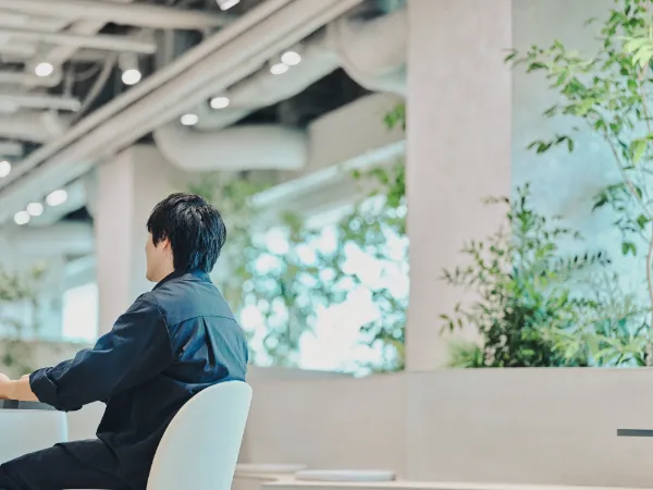  ALTはじまり：広々としたラウンジスペースと、兼原さんの後姿。背中越しに奥の窓とラウンジが見える。ALTおわり