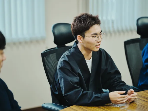 写真:会議室で話すnovactの尾木さん。黒い上着を着て、手を組みながら藤原印刷との鼎談に参加している。