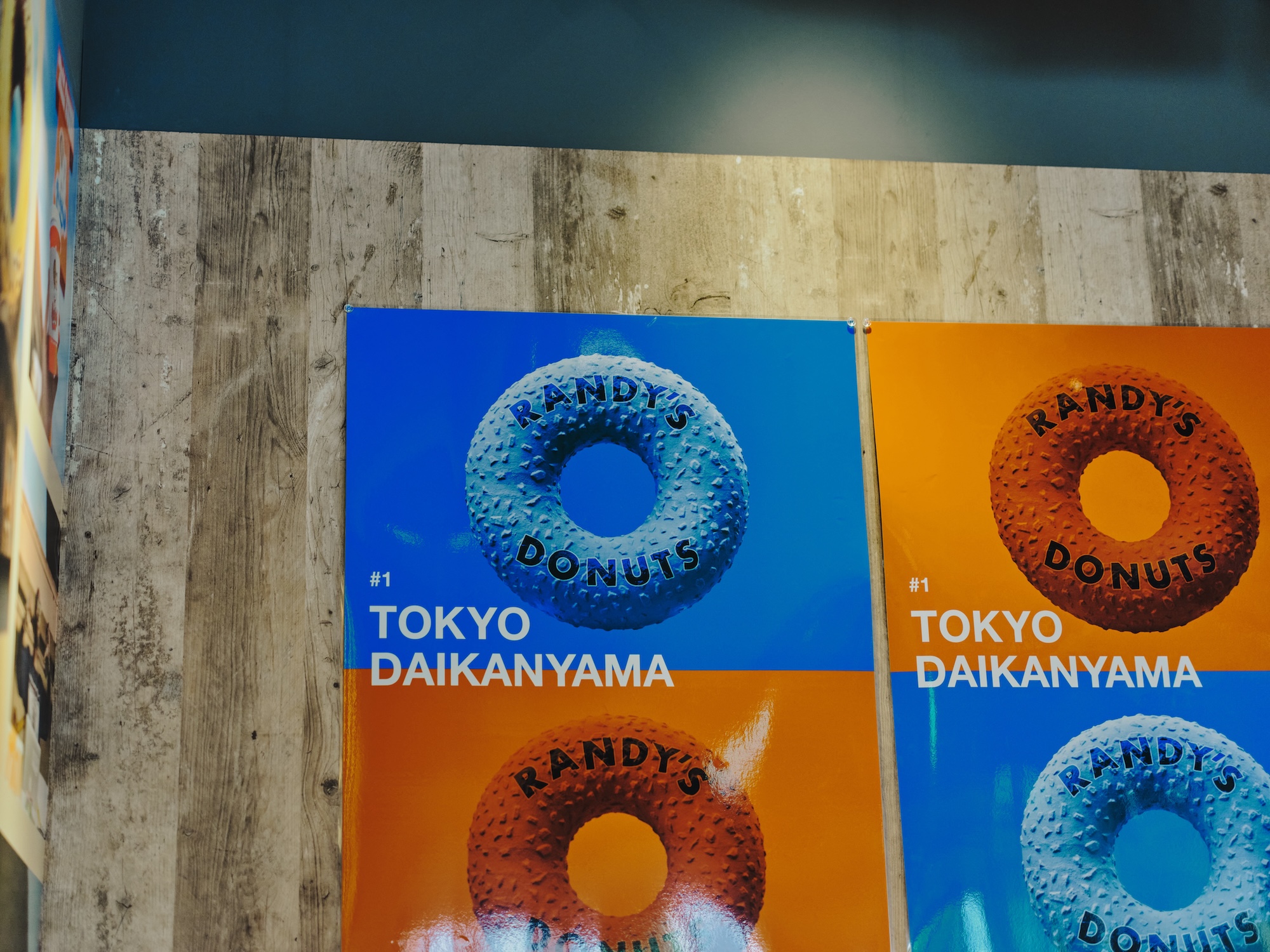 ALTはじまり:店内の壁に飾られた、「RANDY'S DONUTS」のポスター。鮮やかな背景に、ドーナツのロゴがポップに浮かび上がっています。ALTおわり