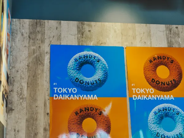 ALTはじまり:店内の壁に飾られた、「RANDY'S DONUTS」のポスター。鮮やかな背景に、ドーナツのロゴがポップに浮かび上がっています。ALTおわり
