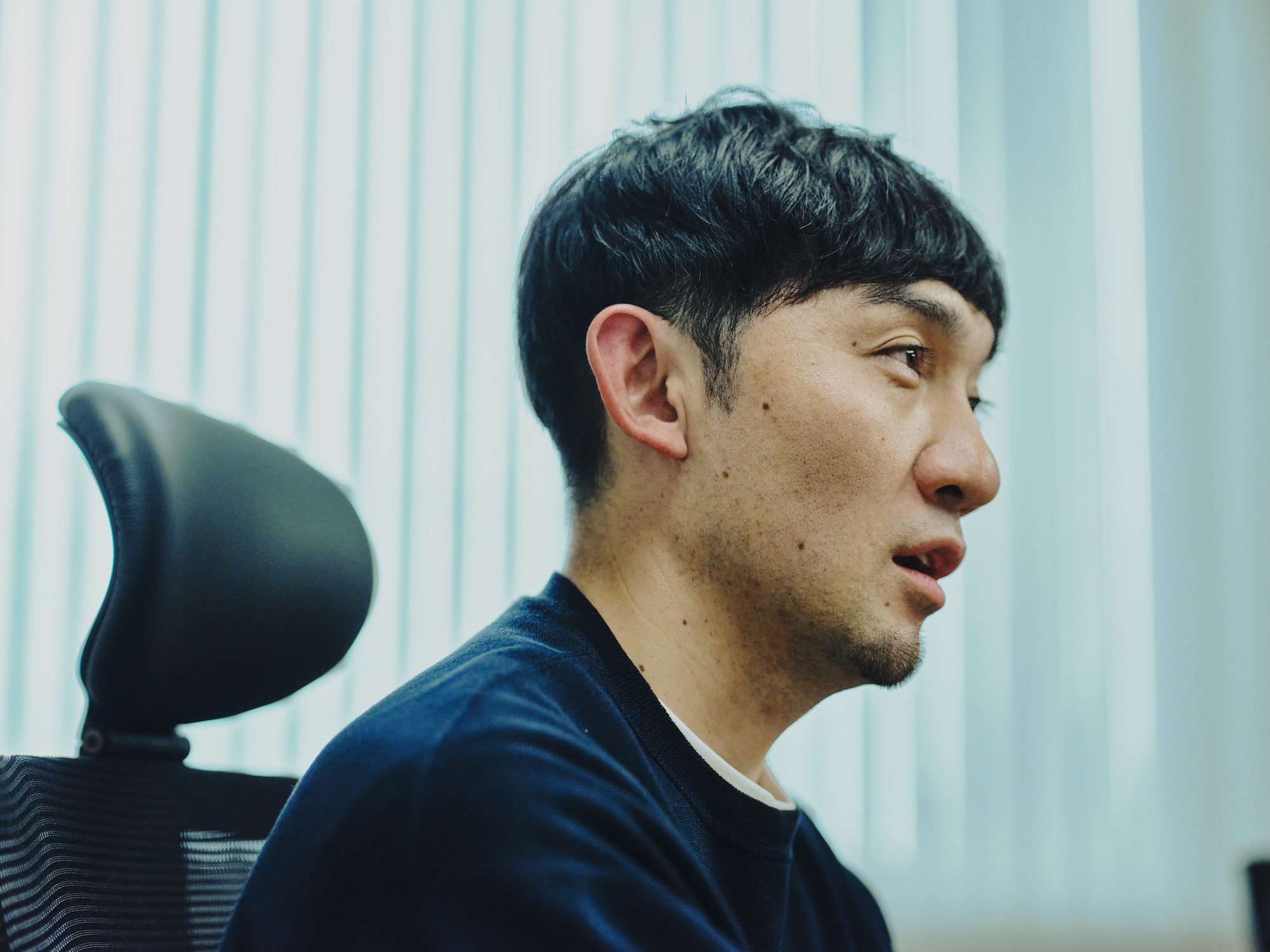 写真:藤原さんの横顔。説明を続けている場面で、視線は前方に向いている。