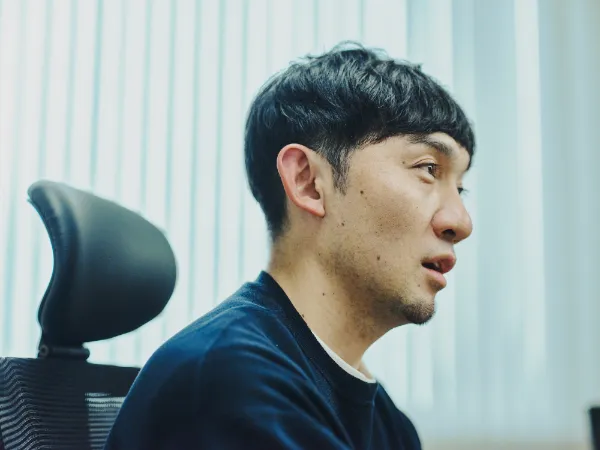 写真:藤原さんの横顔。説明を続けている場面で、視線は前方に向いている。