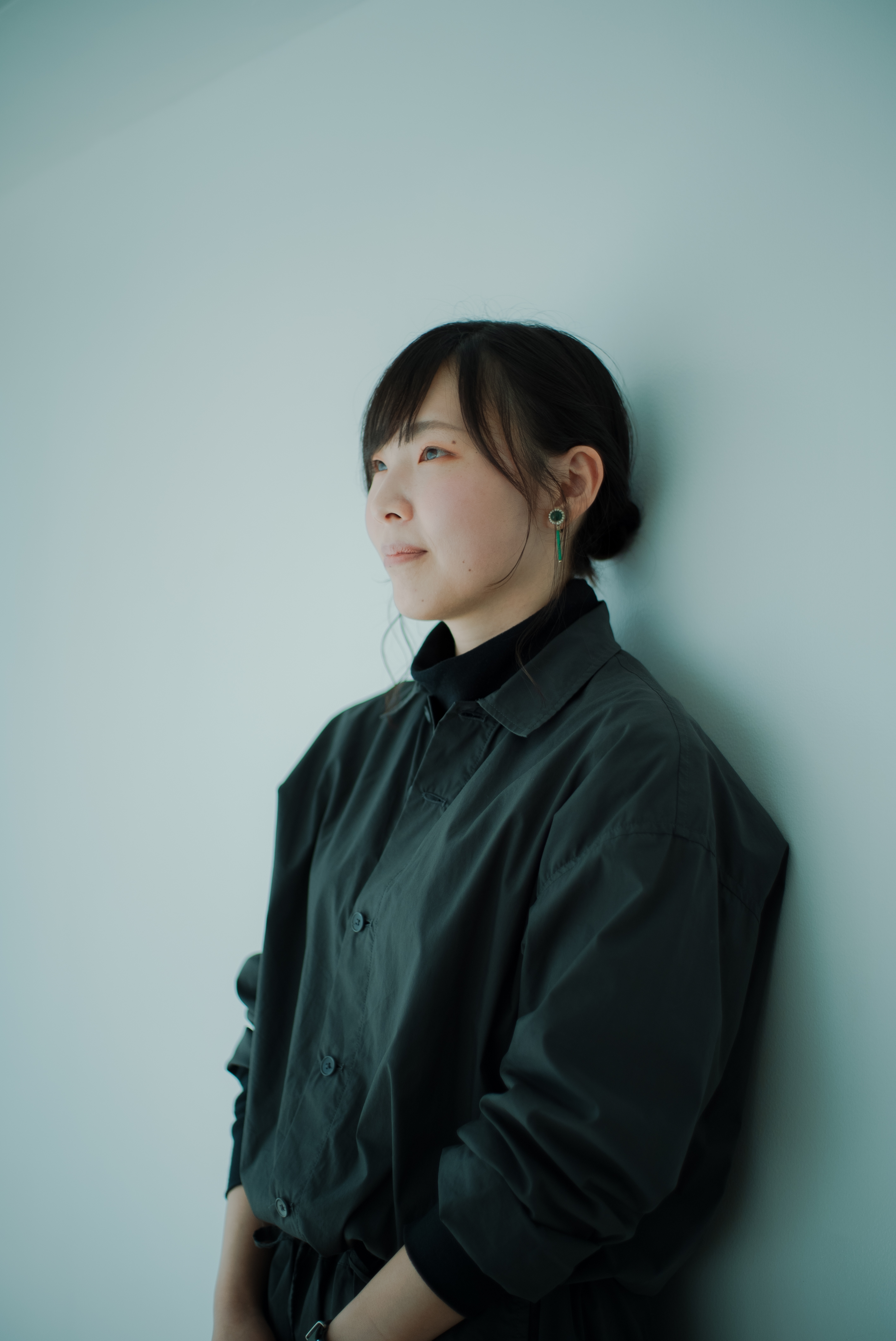 ALTはじまり: 白い壁にもたれかかり、遠くを見つめている大橋さん。ALTおわり