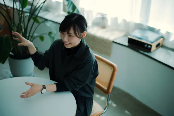  ALTはじまり： 窓際のテーブルで、身振り手振りで話している大橋さん。ALTおわり