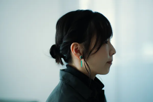  ALTはじまり： 大橋さんの横顔のクローズアップ。エメラルドグリーンのイヤリングを着けている。ALTおわり