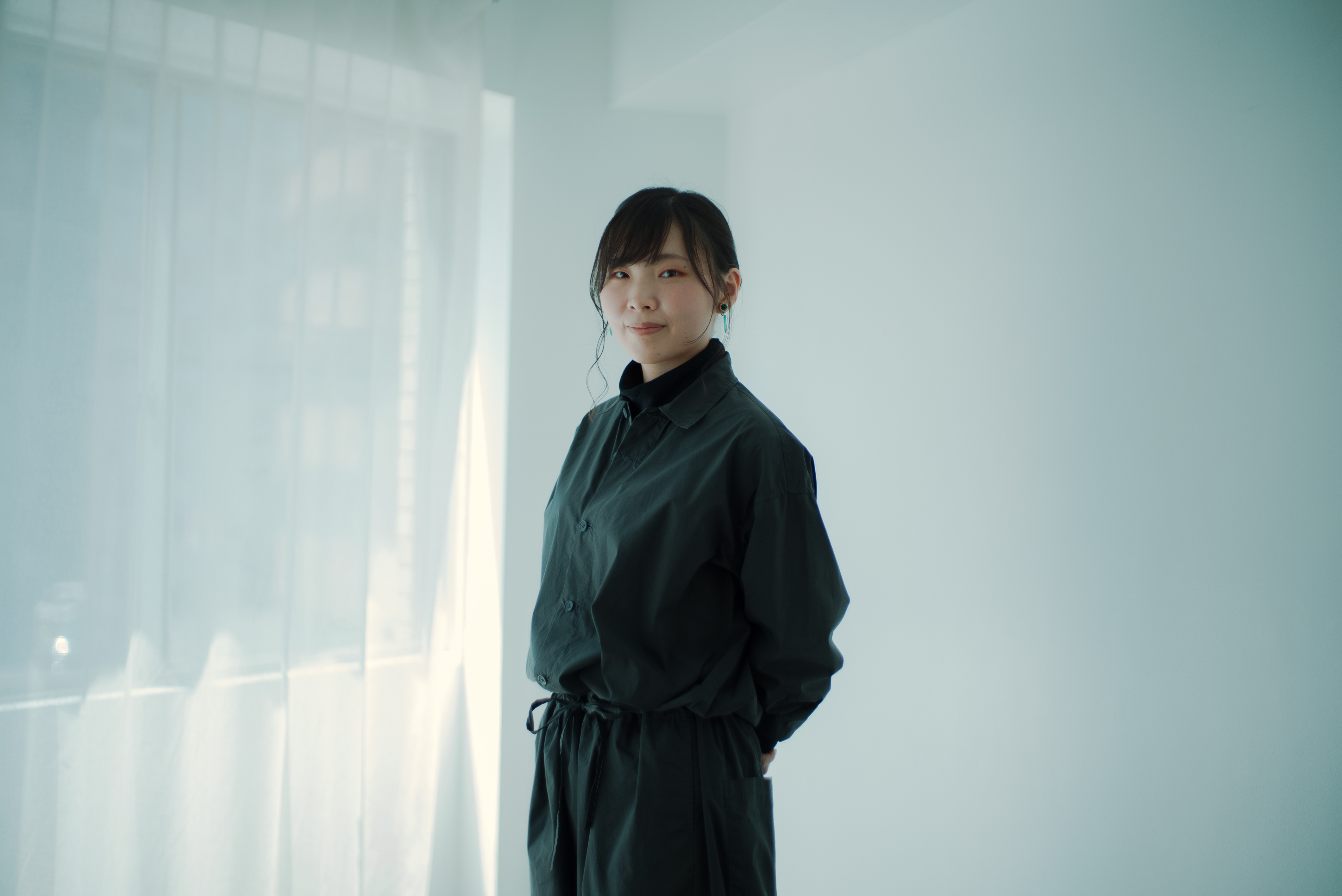 ALTはじまり: 白い部屋の窓際で、カメラに向かって立っている大橋さん。ALTおわり