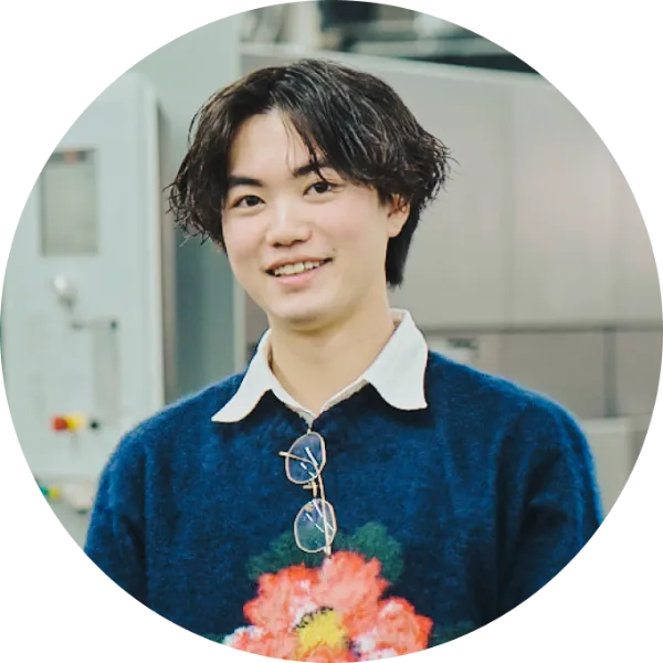 写真:novact・速水駿さんのポートレート。花柄のニットを着て、優しい笑顔を見せている。