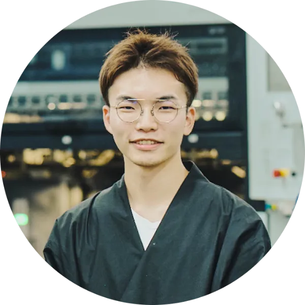 写真:novact・尾木洸太さんのポートレート。黒い羽織風の上着を着て穏やかな表情で立っている。