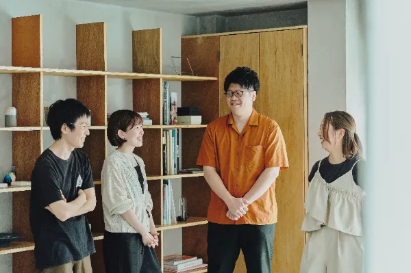 ALTはじまり:棚の前で談笑するcaroaのメンバー4人。右から2番目のオレンジ色のシャツを着た人物が葉栗さん。ALTおわり