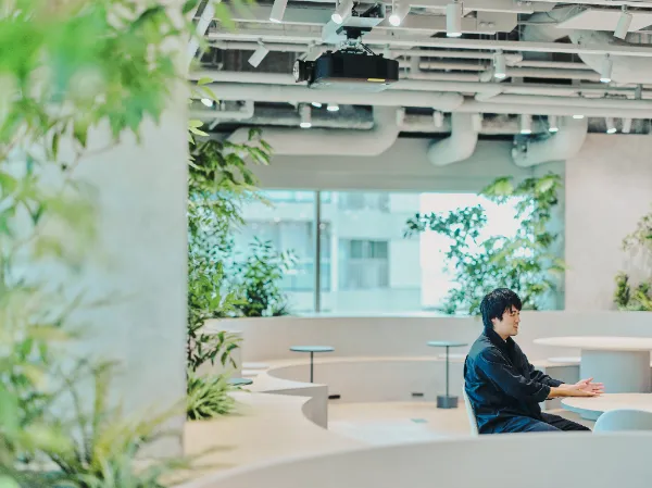 ALTはじまり:開放的なラウンジで、丸テーブルに向かって座る兼原さん。ALTおわり