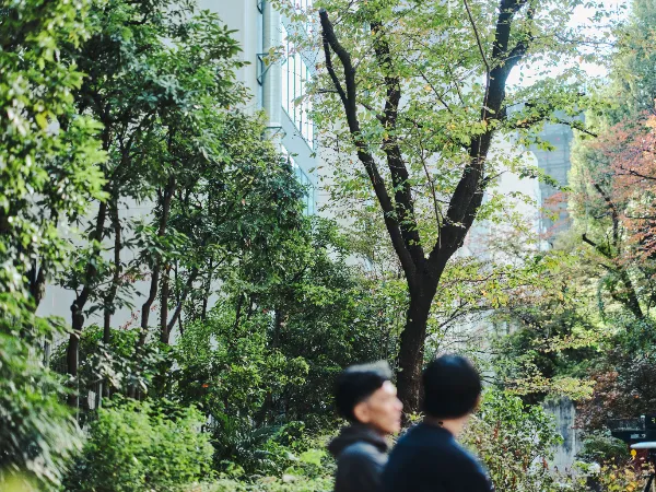 ALTはじまり:緑の多い公園を並んで座っている石井さんと高橋さん。人物に軽いボケがあり、周囲の木々の鮮やかさが際立っている。ALTおわり