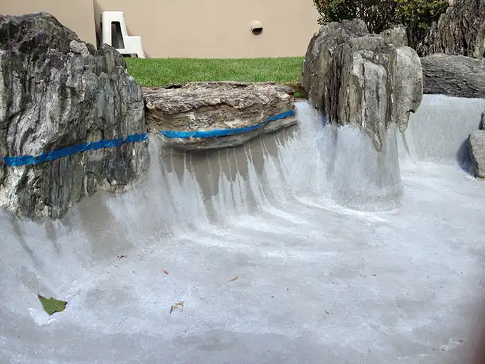 石の表面を養生テープで保護し、立ち上がり部分まで丁寧に防水材を塗布した状態。