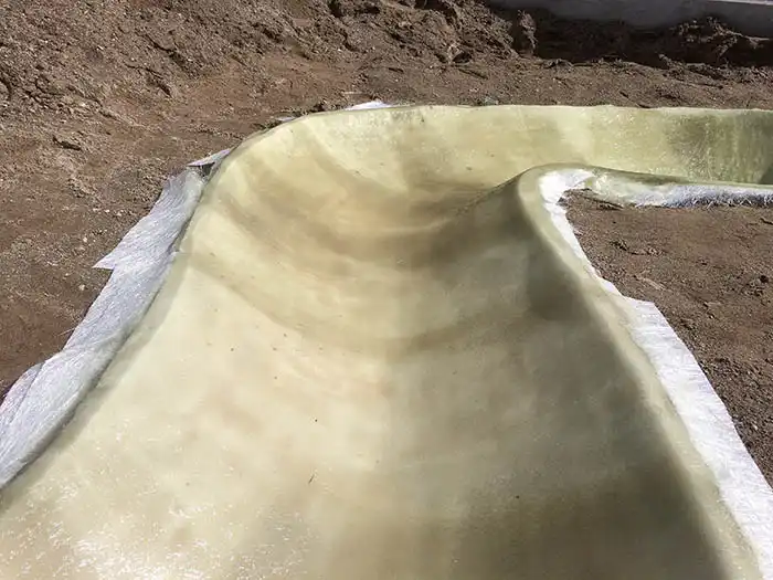 防水層をさらに強化するため、繊維状の素材（FRPなど）を重ねて塗り固めている接写画像。