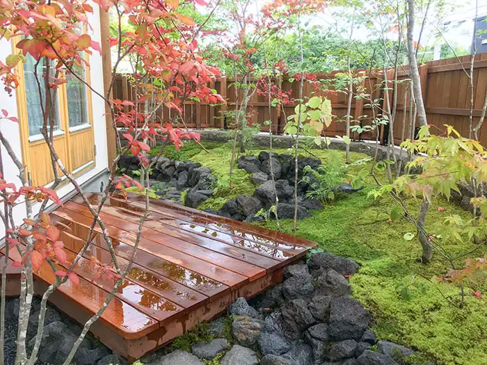 完成した庭の様子。ウッドデッキの横を黒い溶岩石で縁取られた流れが通り、瑞々しい苔と庭木が美しい景観。