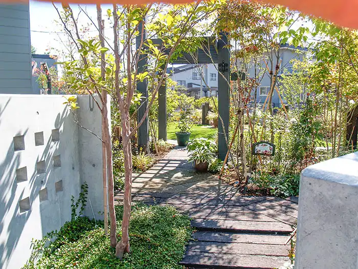 植栽に囲まれた住宅アプローチと門柱、自然素材を活かしたガーデンデザイン