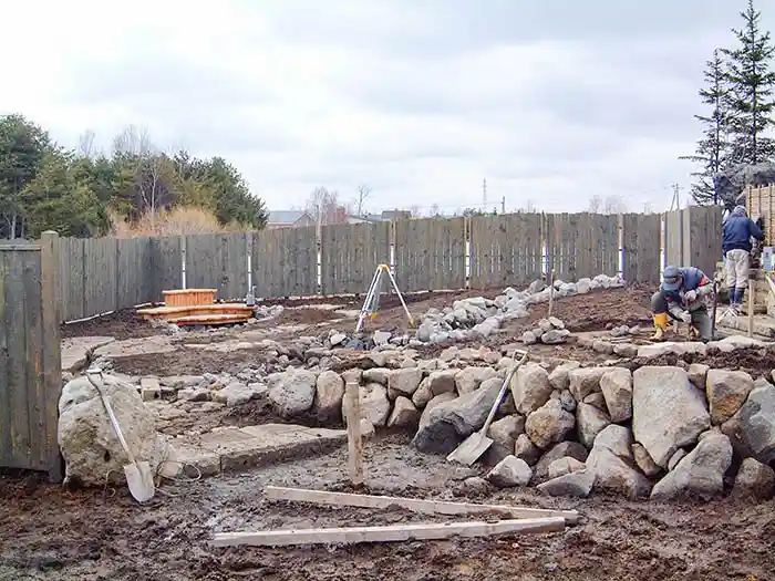 傾斜地に石を積み上げ、土留めを兼ねた自然な石垣（護岸）を一つひとつ組み上げている様子。