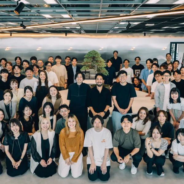 写真、Studioメンバーの集合写真。テーブルを囲んで50~70人ほどが並んでいる