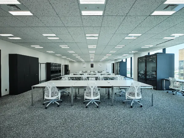 写真、Studioオフィスの様子。デスク、チェアが並べられた執務スペース。窓際には一人用ミーティングが配置されている。