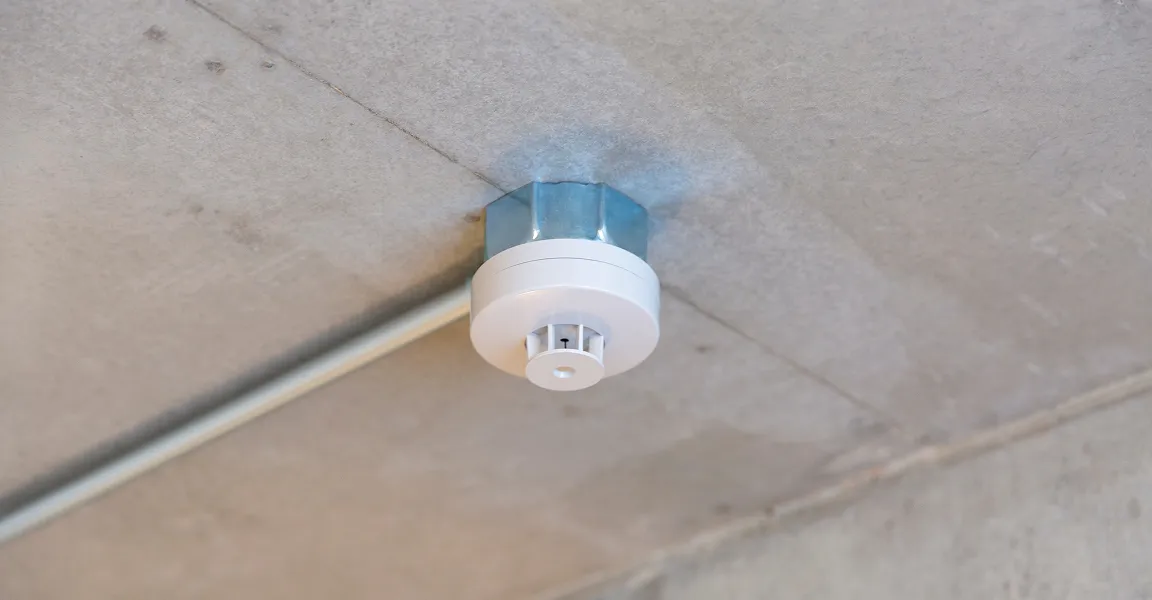 天井に設置された火災感知器を点検する消防設備管理の様子