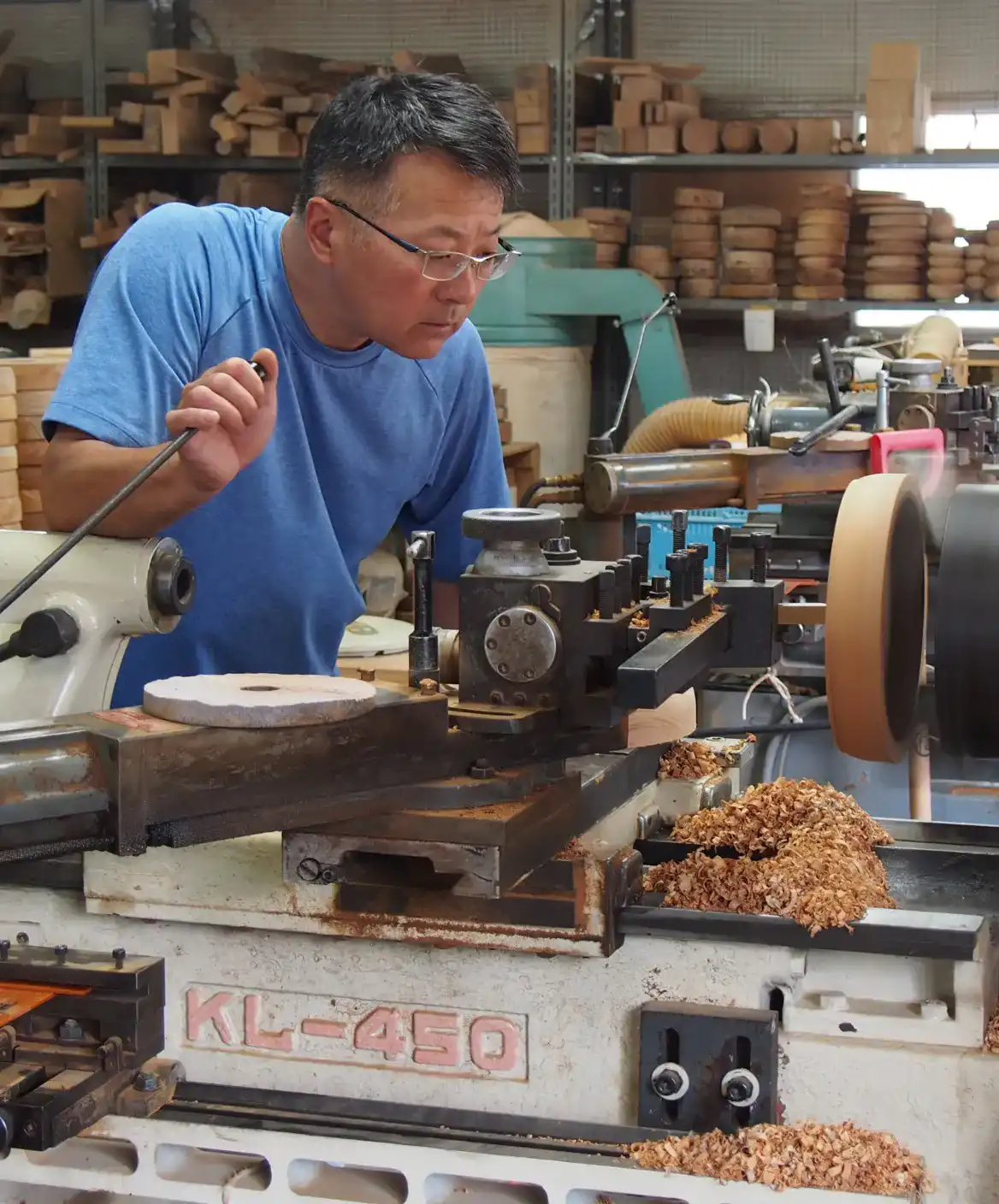 ベテラン職人が木工所で旋盤を使って木材を丸く加工している様子