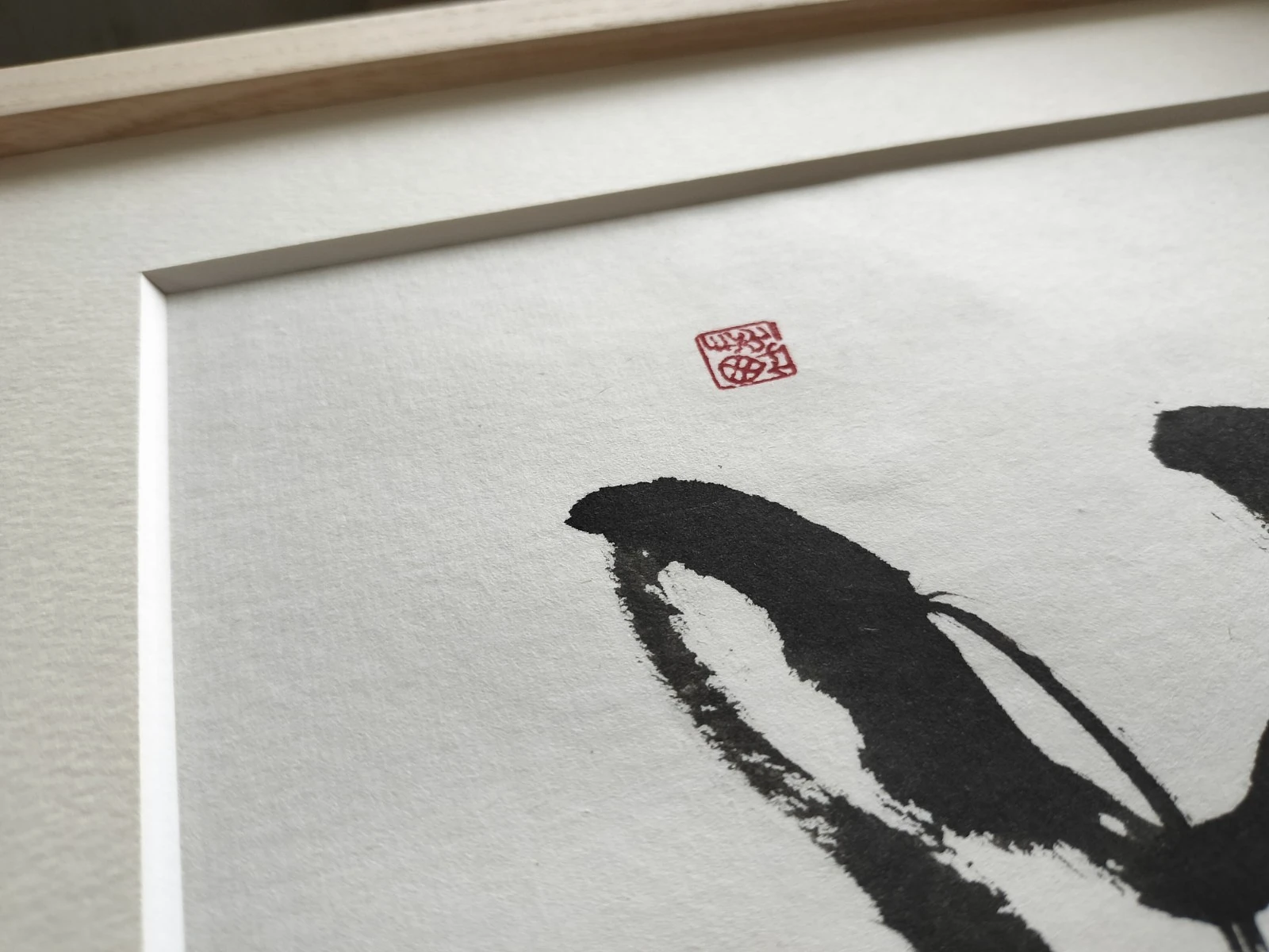 Close-up of original hand-brushed Japanese calligraphy showing sumi ink texture, paper surface, and a red seal.