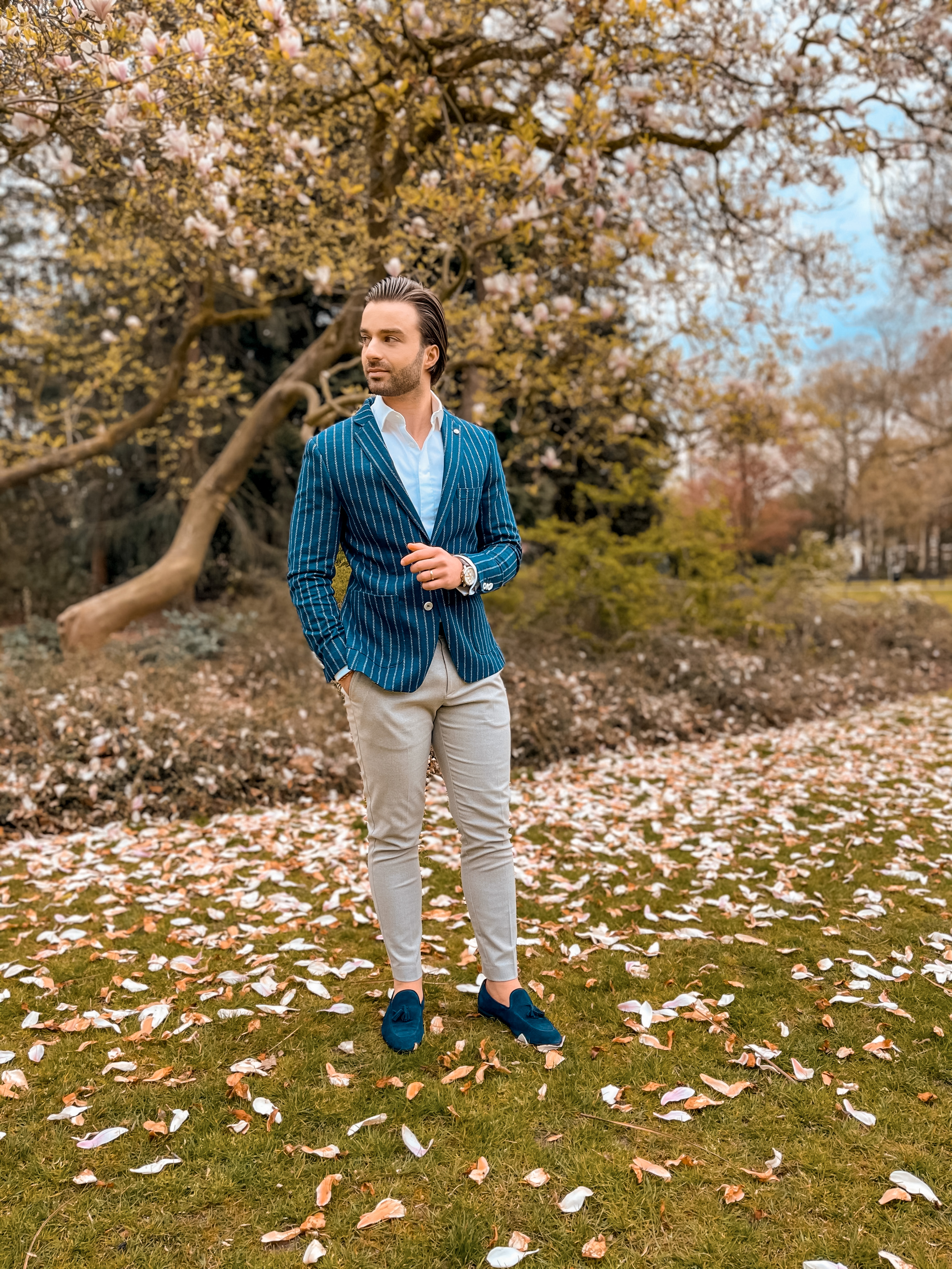 Looking elegant wearing a stripped blazer with a white shirt, beige  trousers and blue suede loafers