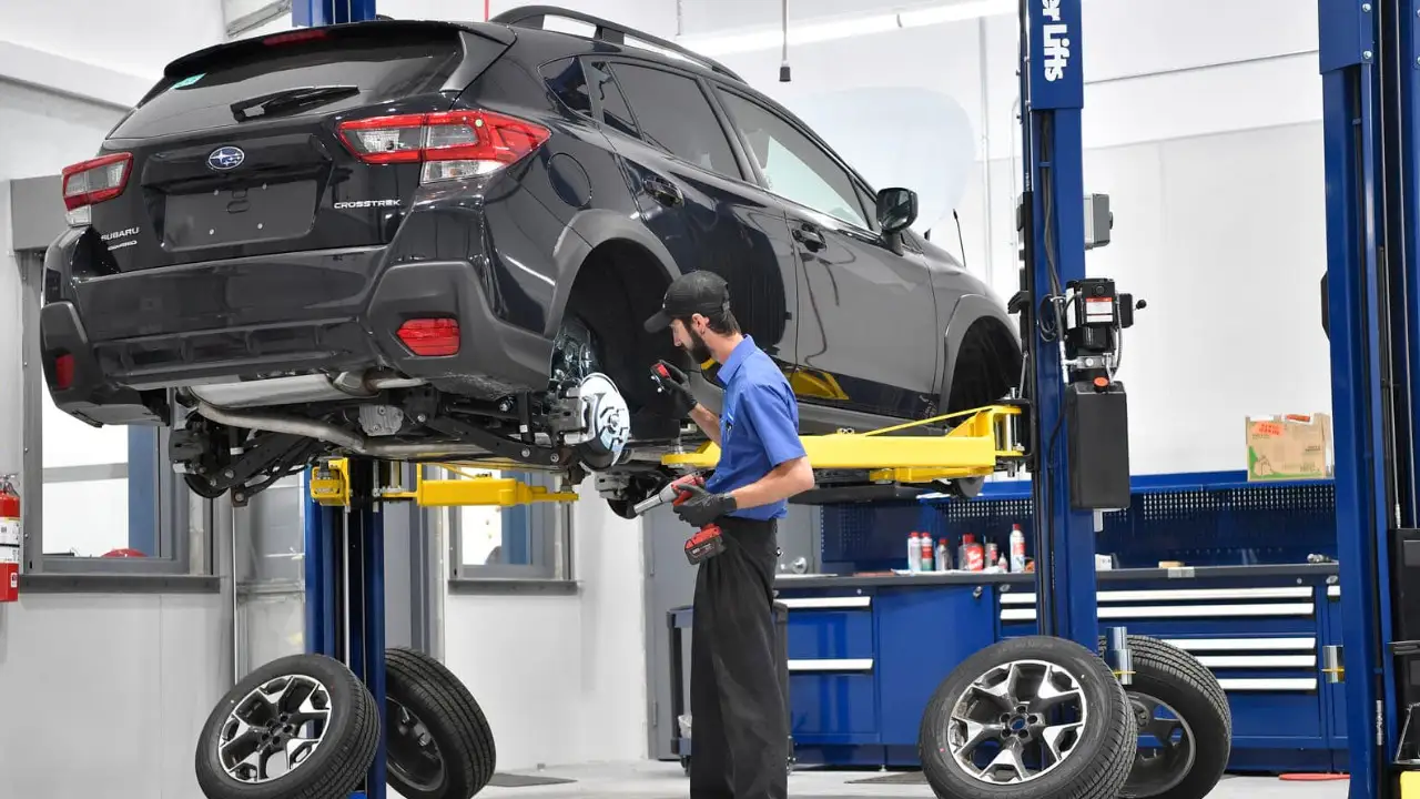 Technicien effectuant des réparations sur un Subaru en atelier, un facteur à considérer avant de remplacer son véhicule.