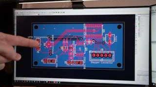 Adam pointing at his initial PCB design on a monitor.