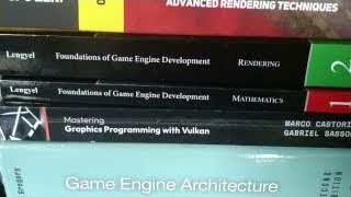 A stack of books on game engine development, mathematics, and graphics programming, showing the depth of study required for expertise.