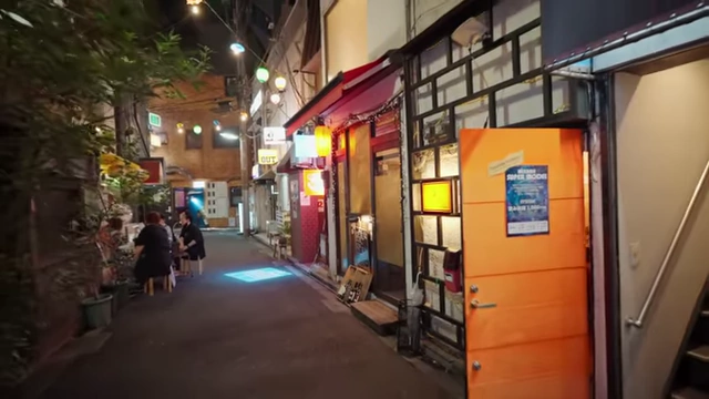 Narrow street with people sitting outside a bar