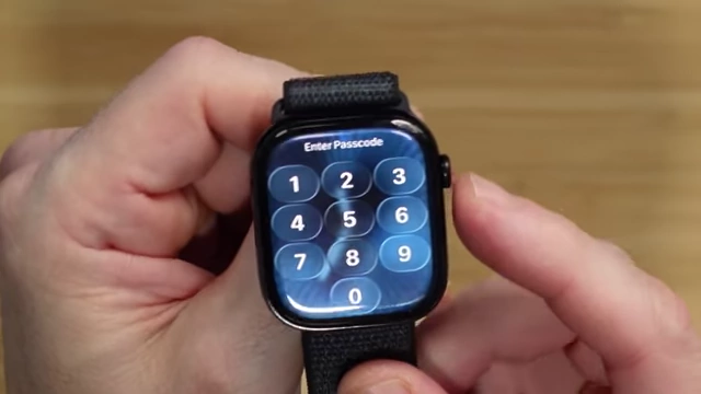 The Apple Watch passcode entry screen, demonstrating the "Liquid Glass" effect on the number buttons.