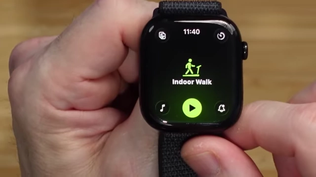 A detailed view of the redesigned Apple Watch Workout app interface, showing options for music, play/pause, and notification settings arranged in the corners.