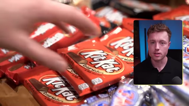 A hand picking up a KitKat chocolate bar from a pile of similar candy, demonstrating a "fun food" that might be a trigger for overeating.