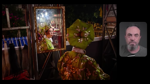 A performance artist in traditional attire looks at her reflection in a mirror, centered in the frame to create a sense of intimacy and dialogue.