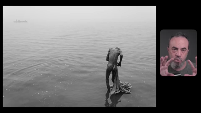 A lone person wades in a vast, misty body of water, illustrating how to compose a single subject within a wide horizontal frame while being mindful of empty space.