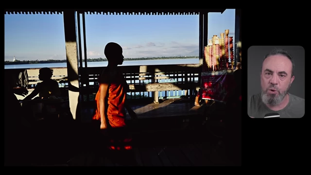 A child stands silhouetted in a doorway, framed by architectural elements that direct attention to the subject and the bright outdoor scene.
