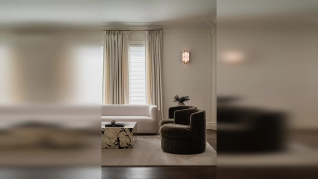 A sophisticated living room featuring neutral colors, a white sofa, and a dark armchair, demonstrating an elevated design.