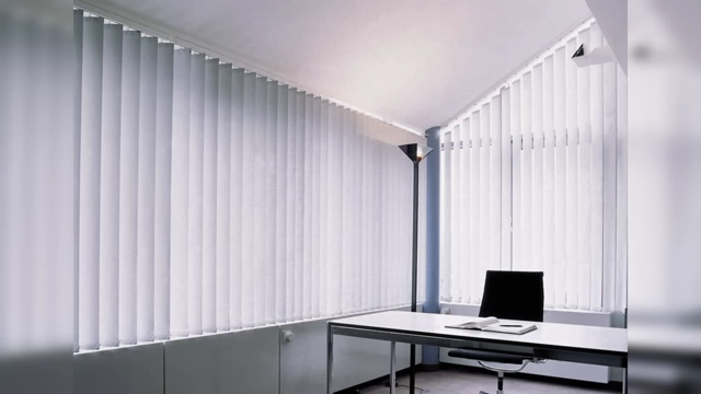 An office space with large vertical white plastic blinds covering the windows.