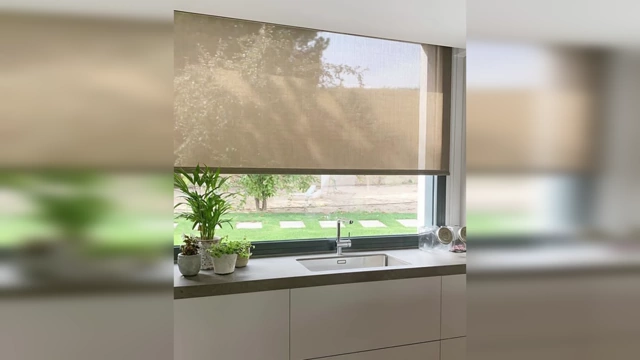 A kitchen window with a clean, minimal roller shade, demonstrating a more modern and elegant alternative to traditional blinds.