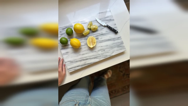 A kitchen counter with lemons and limes on a beautiful, authentic marble cutting board, showing how real materials can be incorporated in small, tasteful ways.