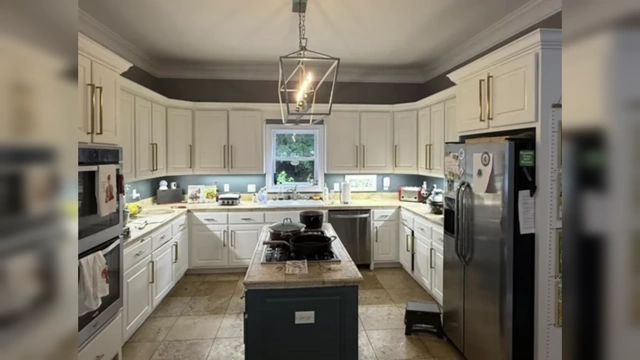 A modern kitchen with white cabinets extending seamlessly all the way to the ceiling, creating a clean, custom, and elongated look.