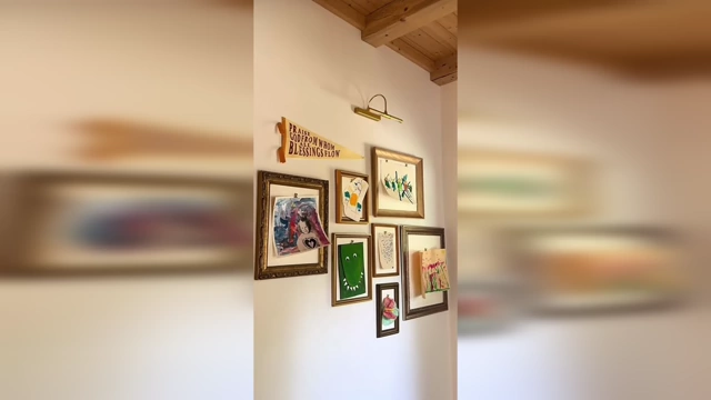 A gallery wall filled with a variety of framed artwork, including what appears to be personal drawings and illustrations, creating a unique and personal aesthetic.