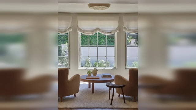 A living room with large windows covered by elegant Roman blinds, which soften the light and add texture.